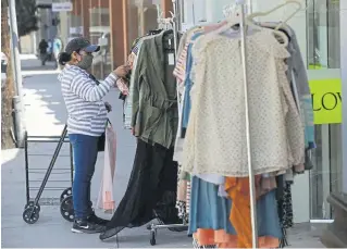  ?? Marcio Jose Sanchez, The Associated Press ?? A woman shops for clothes Wednesday in Los Angeles. A report released Friday showed consumer spending tumbled 17.3% for durable goods, 16.2% for non-durables and 12.2% for services as the pandemic shuttered businesses and forced layoffs.