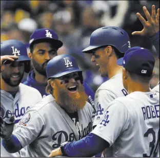  ?? Jeff Roberson The Associated Press ?? Los Angeles’ Justin Turner is greeted by manager Dave Roberts (30) after hitting a two-run home run in the eighth inning of Game 2 against Milwaukee.