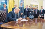  ?? EVAN VUCCI/ASSOCIATED PRESS ?? President Donald Trump signs an executive order implementi­ng a federal government hiring freeze Monday in the Oval Office.