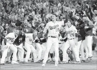  ?? Robert Gauthier Los Angeles Times ?? BELLINGER (35) leads the welcoming committee at home plate after Muncy’s home run in the 18th inning. The game lasted longer than all four games of the 1939 World Series combined.