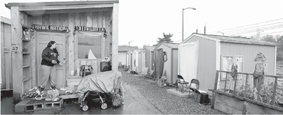  ?? ELAINE THOMPSON, THE ASSOCIATED PRESS ?? Eva Stough opens the door to her tiny house, where she lives with her partner and baby, at an encampment in Seattle.