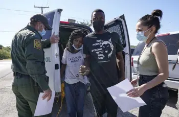  ?? Julio Cortez, The Associated Press ?? A U.S. Customs and Border Protection agent, left, drops off a migrant couple to a member of a humanitari­an group after their release from custody Friday in Del Rio.