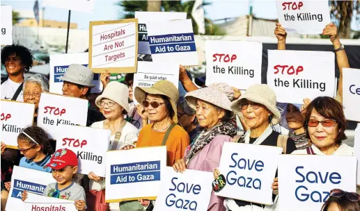  ?? (AFP/via Getty Images) ?? TRAVELERS ABOARD the Panama-flagged cruise ship ‘Pacific World’ gather with signs in solidarity with Palestinia­ns in the Gaza Strip in November.