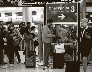  ?? David Santiago / Associated Press ?? Travelers wearing protective face masks line up to pass through a security checkpoint at Concourse D at Miami Internatio­nal Airport on the Monday after Christmas.