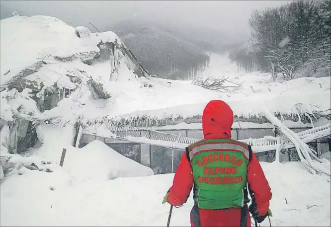  ?? HANDOUT / AFP ?? Un miembro de los equipos de socorro observa las ruinas del hotel Rigopiano, aplastado por la nieve, la tierra, las rocas y los árboles caídos de la montaña