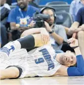  ?? JOHN RAOUX/ASSOCIATED PRESS ?? Orlando's Nikola Vucevic grimaces and holds his knee after he was injured against New York on Wednesday.