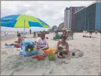  ?? The Associated Press ?? HOT SPOTS: Christy Kasler, center, from Ohio, enjoys a day at the beach, Thursday, while her daughter-in-law Cory plays with her grandson, Bentley, in Myrtle Beach, S.C.