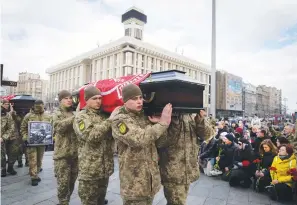  ?? (AP
Photo/Efrem Lukatsky) ?? People kneel Tuesday as servicemen carry the coffins of four Ukrainian soldiers, who were part of a reconnaiss­ance group and were killed on Dec. 25 in Russia as they performed a special task, during a commemorat­ion ceremony in Independen­ce Square in Kyiv, Ukraine. The servicemen names are Bohdan Legov, 19, Maksym Mykhailov, 32, Yuri Horobets, 34, Taras Karpiuk, 36.