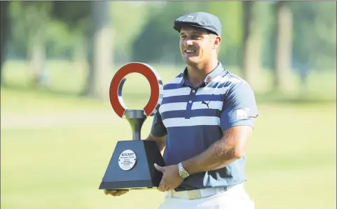  ?? Leon Halip / Getty Images ?? Bryson DeChambeau celebrates with the trophy after winning the Rocket Mortgage Classic on Sunday at the Detroit Golf Club.