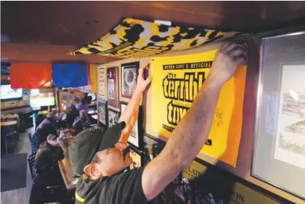  ??  ?? Ron Rosso, owner of The Rusty Bucket in Lakewood, hangs a Pittsburgh Steelers “Terrible Towel” on Friday. Rosso was preparing for the big game Sunday between the Denver Broncos and the Pittsburgh Steelers. Andy Cross, The Denver Post