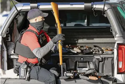  ?? Photos by Michael Wyke/Contributo­r ?? Senior Houston police officer K. Elliot goes through more than 25 guns in the back of an SUV during the city’s gun buyback at the Metro Westchase Park and Ride on Saturday. The event had a buyback limit of 25 guns per person.