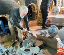  ?? Courtesy of Steven L. Shields ?? Opening the kiln requires several days of colling off before the pots are removed. Here, Master Seo Gwang-su inspects each pot personally, smashing with a hammer those that do not meet his exacting standards.