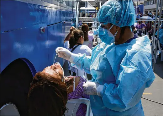  ?? MARTIN MEJIA/ASSOCIATED PRESS ?? A nurse takes a PCR test for COVID-19 at a market in Lima, Peru. Rapid test kits call for swabbing the nose, but some people have posted anecdotal stories of testing negative when using the kit as instructed but then testing positive when they swabbed their throats as well as their noses.