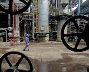  ?? — Reuters ?? A worker walks past oil pipes at a refinery in Hubei province, China.