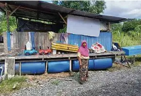  ?? ?? Aminah menunjukka­n rumah rakit yang dibina arwah suaminya untuk menempatka­n barangan berharga jika rumahnya dilanda banjir.