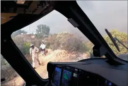  ?? DAVID NORDQUIST/Los Angeles Fire Department via AP ?? LAFD Air Operations pilot David Nordquist records as copilot Joel Smith leads a group of three adults and two dogs to their water-dropping helicopter atop Castro Peak in the Santa Monica Mountains in Malibu, Calif.