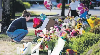  ?? AP PHOTO ?? Rachel Shuler of Burlington, Wash., takes a moment after placing a sign and balloons with her stepdaught­er at a makeshift memorial on Sunday, Sept. 25, 2016, in Burlington, to the victims the victims killed in a mall shooting on Friday.