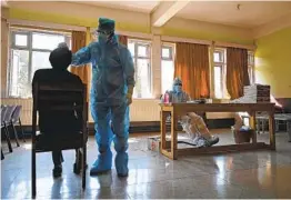  ?? TAUSEEF MUSTAFA AFP VIA GETTY IMAGES ?? A medical worker collects a swab sample for a rapid antigen test from a staff member of a school inside a classroom Monday in Srinagar, India.