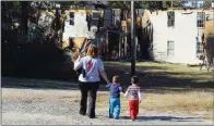  ?? TAMMY KEITH/RIVER VALLEY & OZARK EDITION ?? Monica Fortune walks with her three children from Grassy Lakes Apartments in Mayflower to Queens Manor Apartments, where she lived when one of the complex’s buildings caught fire Oct. 14. Fortune said she lost everything in the fire, but she has...