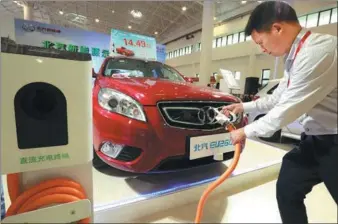  ?? SHI YAN / FOR CHINA DAILY ?? charges an electric car at an auto expo in Haikou, capital of Hainan province.