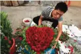  ??  ?? A florist preparing a heart-shaped bouquet of roses ahead of China's Valentine's Day, at a flower market in Beijing.