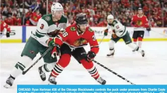  ??  ?? CHICAGO: Ryan Hartman #38 of the Chicago Blackhawks controls the puck under pressure from Charlie Coyle #3 of the Minnesota Wild at the United Center in Chicago, Illinois. The Blackhawks defeated the Wild 4-1. —AFP