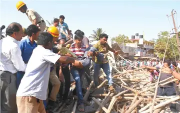  ?? — AFP photo ?? Rescue workers and members of the public carry a survivor after he was found under the rubble of an under-constructi­on multi-storey building that collapsed in Dharwad district of Karnataka.