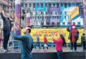  ?? CALLA KESSLER/THE NEW YORK TIMES ?? Getting ready to welcome 2022: People take photograph­s near a New Year’s Eve show stage Thursday in New York’s Times Square. Mayor Bill de Blasio said the celebratio­n to ring in the new year with the annual ball drop will go on as planned despite record numbers of COVID-19 infections in the city and around the country.