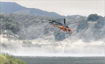  ?? Photograph­s by Allen J. Schaben Los Angeles Times ?? A HELICOPTER battling the Whittier fire draws water from Lake Cachuma. The blaze, which started about 2 p.m. Saturday, initially trapped some 80 campers at the Circle V Ranch Camp.