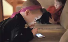  ?? STEVEN SENNE, AP ?? Nolan Young, 3, front, looks at a smartphone while his brother Jameson, 4, uses a tablet in Boston. Pediatrici­ans say limited screen time is OK as long as kids have time for other activities.