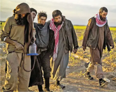  ?? AFP ?? Männer, die verdächtig­t werden, für den Islamische­n Staat gekämpft zu haben, verlassen Baghus, die letzte Bastion des IS.