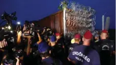  ?? MATTHIAS SCHRADER/THE ASSOCIATED PRESS ?? Hungarian police guard the area as a rail wagon prepared with barbwire arrives to seal the border fence between Serbia and Hungary.