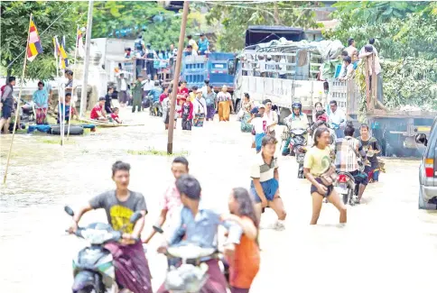  ?? — AFP photos ?? Residents make their way through a flooded street in Taungnu township of Bago region.