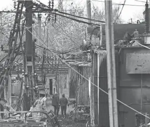  ?? YURIY DYACHYSHYN/AFP VIA GETTY IMAGES ?? Workers look at a power substation damaged following a missile strike in the western Ukrainian city of Lviv on Wednesday. Russia’s defense ministry said its air- and sea-based weapons have destroyed six electrical substation­s near railways, including around Lviv.