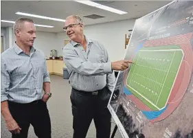  ?? JOELLE KOVACH EXAMINER ?? City recreation co-ordinator Rob Anderson (left) and city community services commission­er Allan Seabrooke (right) look at the design for a new artificial sports field planned for Holy Cross Secondary School. About 25 people attended a public meeting Monday night.