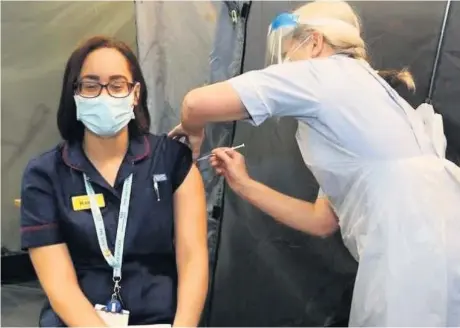  ?? Picture: Gloucester­shire Hospitals NHS Foundation Trust ?? Nurse Kerry Holden receives the new Covid-19 vaccinatio­n from fellow nurse Lorna – making her the first in the county to have the jab