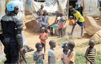  ?? PICTURE: REUTERS ?? WATCHFUL: A UN peacekeepe­r keeps watch as children gather in a camp for displaced civilians in Juba, South Sudan.