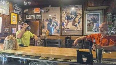  ?? Lake Fong/Post-Gazette ?? John Shrader, left, 21, of Washington, Pa., has a beer after work at Peter’s Pub on Thursday in Oakland. Peter’s Pub is closing next Friday after 44 years in business.