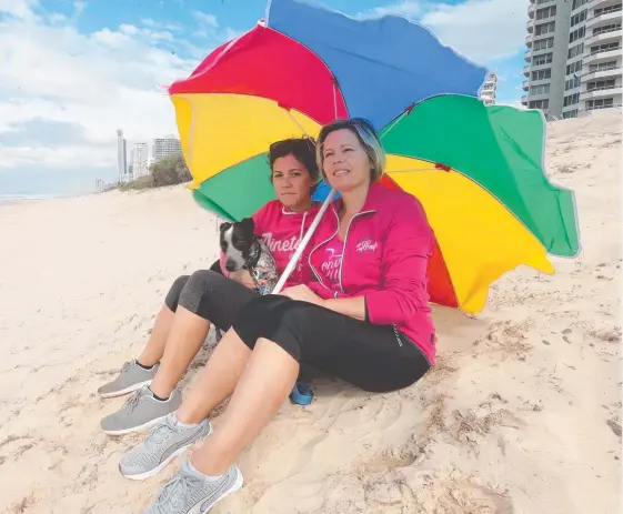  ?? Picture: MIKE BATTERHAM ?? Karen Marin and Wendy Guidolin, and her dog Micky, try and stay dry at Main Beach yesterday.