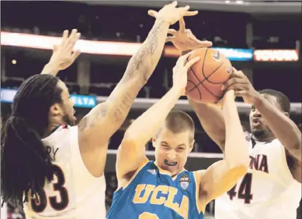  ?? Luis Sinco
Los Angeles Times ?? UCLA’S TRAVIS WEAR
gets caught between Arizona’s Jesse Perry, left, and Solomon Hill. Wear had 10 points before fouling out.