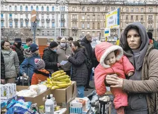  ?? MAURICIO LIMA NYT ?? A just-arrived Ukrainian mother and child receive food distribute­d by volunteers in central Budapest, Hungary, on Saturday. More than 1.4 million Ukrainians have left their country.