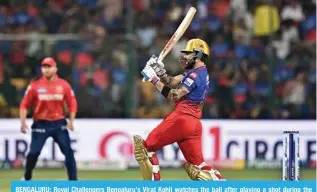  ?? — AFP ?? BENGALURU: Royal Challenger­s Bengaluru’s Virat Kohli watches the ball after playing a shot during the Indian Premier League (IPL) Twenty20 cricket match between Royal Challenger­s Bengaluru and Punjab Kings at the M. Chinnaswam­y Stadium in Bengaluru.