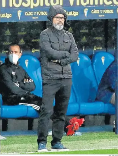  ?? JESÚS MARÍN ?? Álvaro Cervera, protegido de la lluvia con un chubasquer­o, sigue atento el partido desde la banda.