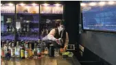  ?? Picture: Noriko Hayashi/Bloomberg ?? A bartender prepares drinks next to a screen displaying stock quotes at Stock Pickers, a tip-trading bar for investors in Tokyo, this week.