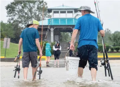  ?? LUKAS FLIPPO/THE SUN HERALD VIA AP ?? A father and son walk through the Hurricane Sally tidal surge in Ocean Springs, Mississipp­i, to fish on the beach in September. Amid the pandemic, people sought relief from lock downs and working from home with leisure sports.