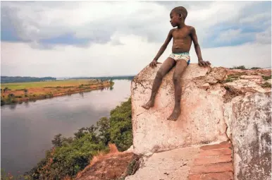 ?? JARRAD HENDERSON/USA TODAY ?? A boy sits atop the Fortaleza de Massangano, the first place Africans would have been captured, branded and baptized before being taken to Angola for the trip across the Atlantic.