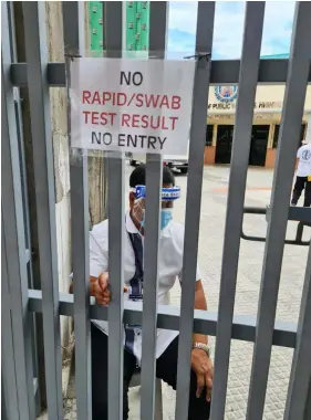  ?? (Chris Navarro) ?? NO TEST, NO ENTRY. A personnel of the DPWH-Pampanga 2nd District Engineerin­g Office guards the gate as visitors are required.to show their rapid Test and swab test before being allowed to enter the compound in Guagua, Pampanga. Strict safety and health protocols are being enforced in all DPWH district offices in Pampanga to ensure that the Coronaviru­s will not infect its personnel.