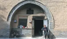  ??  ?? An elderly woman sits in front of her undergroun­d dwelling in Pinglu, Shanxi province.