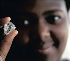  ??  ?? A visitor holds a diamond during a visit to the De Beers Global Sightholde­r Sales in Gaborone. Botswana knows that the breakneck growth fuelled by diamonds in the past will not be repeated.