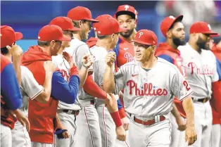  ?? LYNNE SLADKY/AP ?? Phillies manager Joe Girardi high-fives players before a baseball game against the Marlins on Thursday in Miami.